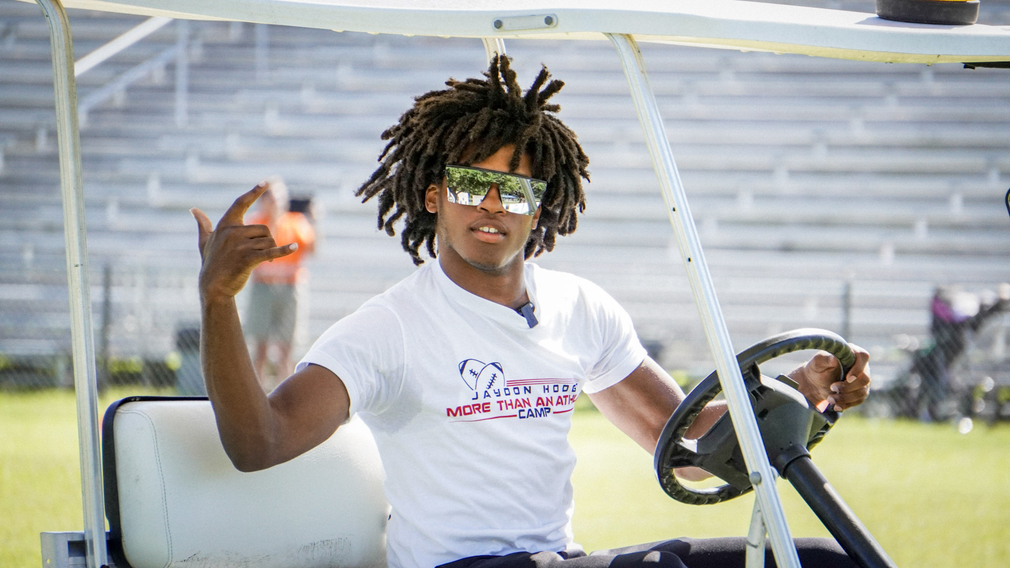 Jaydon driving a golf cart at his football camp